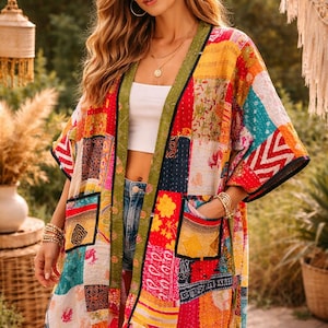 Könnte beinhalten: Bunte Patchwork-Kimono-Jacke mit einer lebendigen Mischung aus roten, gelben, blauen und grünen Stoffen. Die Jacke hat einen grünen Besatz, schwarze Paspeln und zwei Vordertaschen. Das Kleidungsstück wird über einem weißen Oberteil und Jeansshorts getragen.
