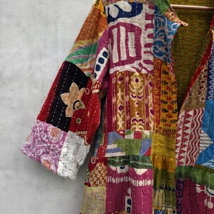 May include: A patchwork jacket in a variety of colors, including red, pink, yellow, and blue. The jacket has a collar and three-quarter sleeves. The fabric is made of different patterned pieces sewn together, creating a unique and colorful design.