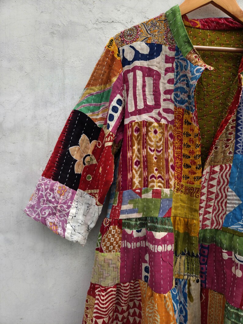 May include: A patchwork jacket in a variety of colors, including red, pink, yellow, and blue. The jacket has a collar and three-quarter sleeves. The fabric is made of different patterned pieces sewn together, creating a unique and colorful design.
