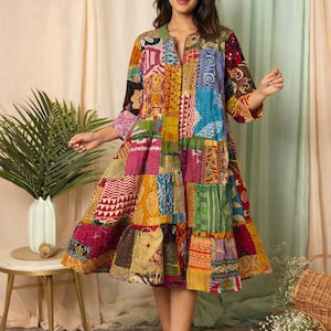 Könnte beinhalten: Ein farbenfrohes Patchwork-Kleid mit einem Stufenrock. Das Kleid hat eine Vielzahl von Stoffmustern in Rot-, Blau-, Gelb- und Grüntönen. Es hat einen V-Ausschnitt und Dreiviertelärmel. Das Kleid ist knielang.