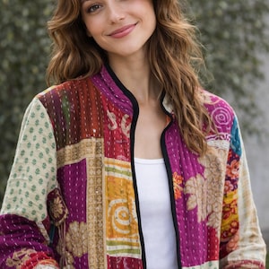 May include: A long-sleeved quilted jacket featuring a patchwork design with various floral and geometric patterns in shades of magenta, cream, yellow, and red. The jacket has a black trim along the front opening and a white tank top underneath.