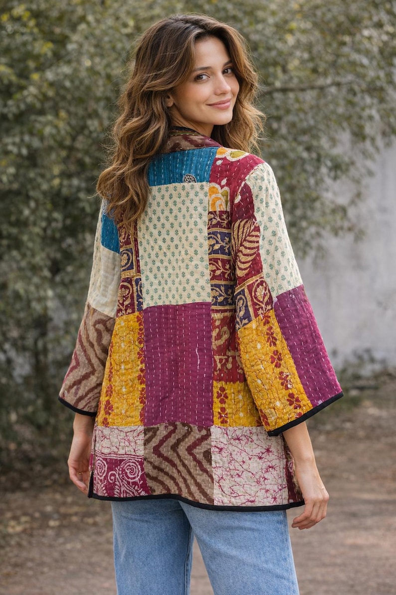 May include: A quilted jacket featuring a patchwork design of various floral and geometric patterns in shades of maroon, mustard yellow, cream, and blue. The garment has three-quarter length sleeves, a straight hem, and black trim along the edges.