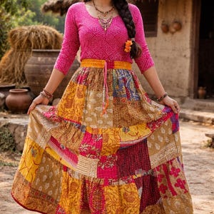 Könnte beinhalten: Eine Frau trägt ein pinkfarbenes Langarm-Oberteil und einen Patchwork-Rock. Der Rock weist eine Vielzahl von Farben auf, darunter Gelb, Pink und Braun. Das Outfit ist mit Schmuck und einem gelben Gürtel versehen. Der Hintergrund umfasst ein Gebäude mit Strohdach und Töpferwaren.