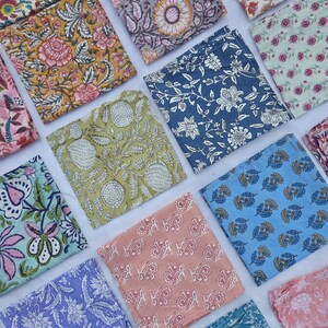 May include: An assortment of colorful, square fabric pieces with floral and botanical patterns. The fabrics feature a variety of colors, including yellow, blue, pink, and green, with intricate designs. The arrangement showcases the diverse patterns and colors.