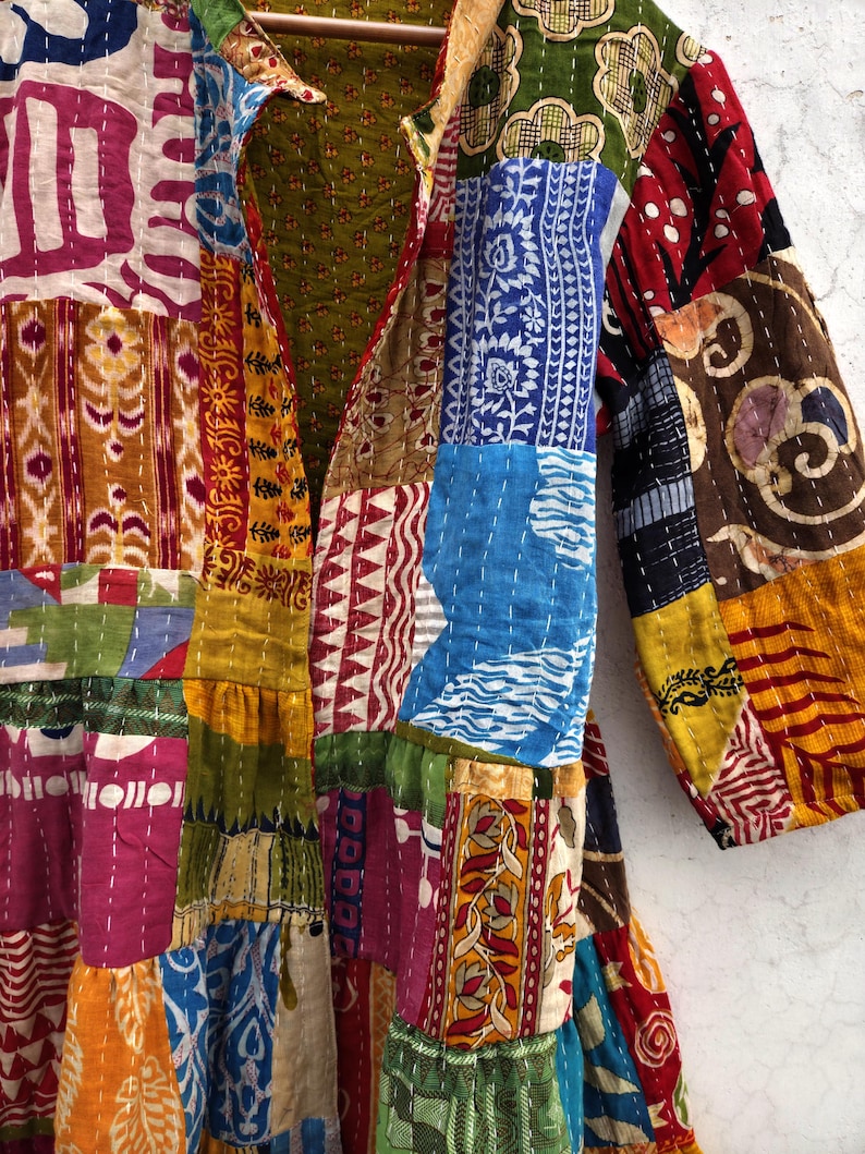 May include: A patchwork jacket with a variety of colorful fabric patterns. The jacket features a mix of floral, geometric, and abstract designs in shades of red, blue, green, yellow, and pink. The jacket has long sleeves and a collar.