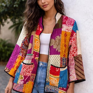 Könnte beinhalten: Bunte Patchwork-Jacke mit verschiedenen Mustern und Farben, darunter Lila, Rot, Gelb und Blau. Die Jacke hat schwarze Paspeln und zwei Vordertaschen. Die Jacke wird offen getragen.