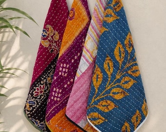 Puede incluir: Cinco piezas de tela acolchada coloridas colgadas en una pared. Las piezas presentan varios patrones y colores, incluyendo burdeos, naranja, morado, rosa y azul. Cada pieza tiene un diseño único, con motivos florales y de hojas.