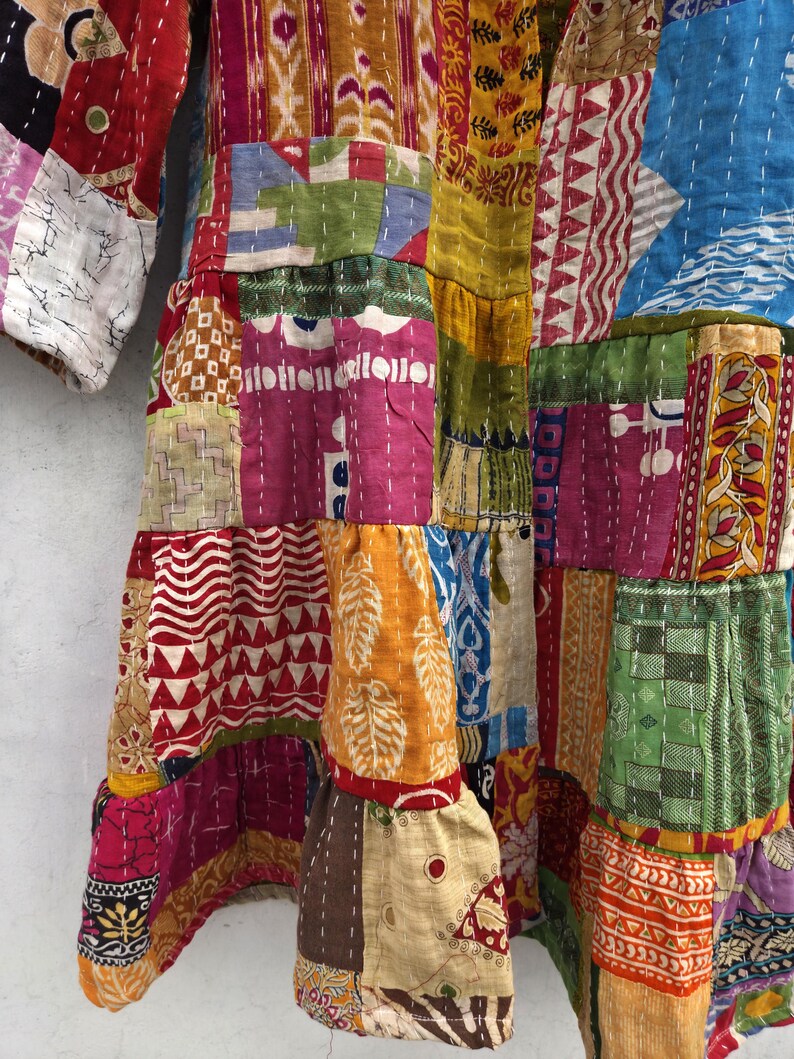 May include: A patchwork garment featuring a vibrant mix of colors and patterns. The design incorporates various fabric pieces stitched together, showcasing a range of textures and hues, including red, yellow, blue, and pink. The garment has a layered appearance with visible seams.
