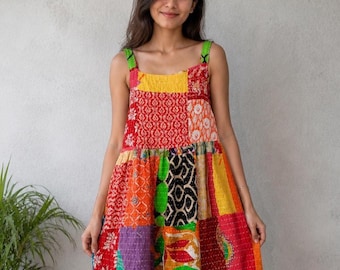 May include: A patchwork mini dress with a vibrant mix of colors and patterns. The dress features a square neckline, wide straps, and a gathered waist. The fabric appears to be a mix of different textiles, creating a unique and eye-catching design.