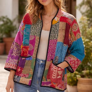 May include: A patchwork jacket with a variety of colorful fabric squares. The jacket has a black trim, pockets, and three-quarter sleeves. The jacket is worn with a white top and blue jeans.