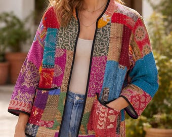 May include: A patchwork jacket with a variety of colorful fabric squares. The jacket has a black trim, pockets, and three-quarter sleeves. The jacket is worn with a white top and blue jeans.