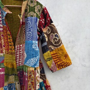 May include: A patchwork jacket with a variety of colorful fabric patterns. The jacket features a collared neckline and long sleeves. The design includes red, blue, yellow, and green patches, creating a vibrant and unique look.