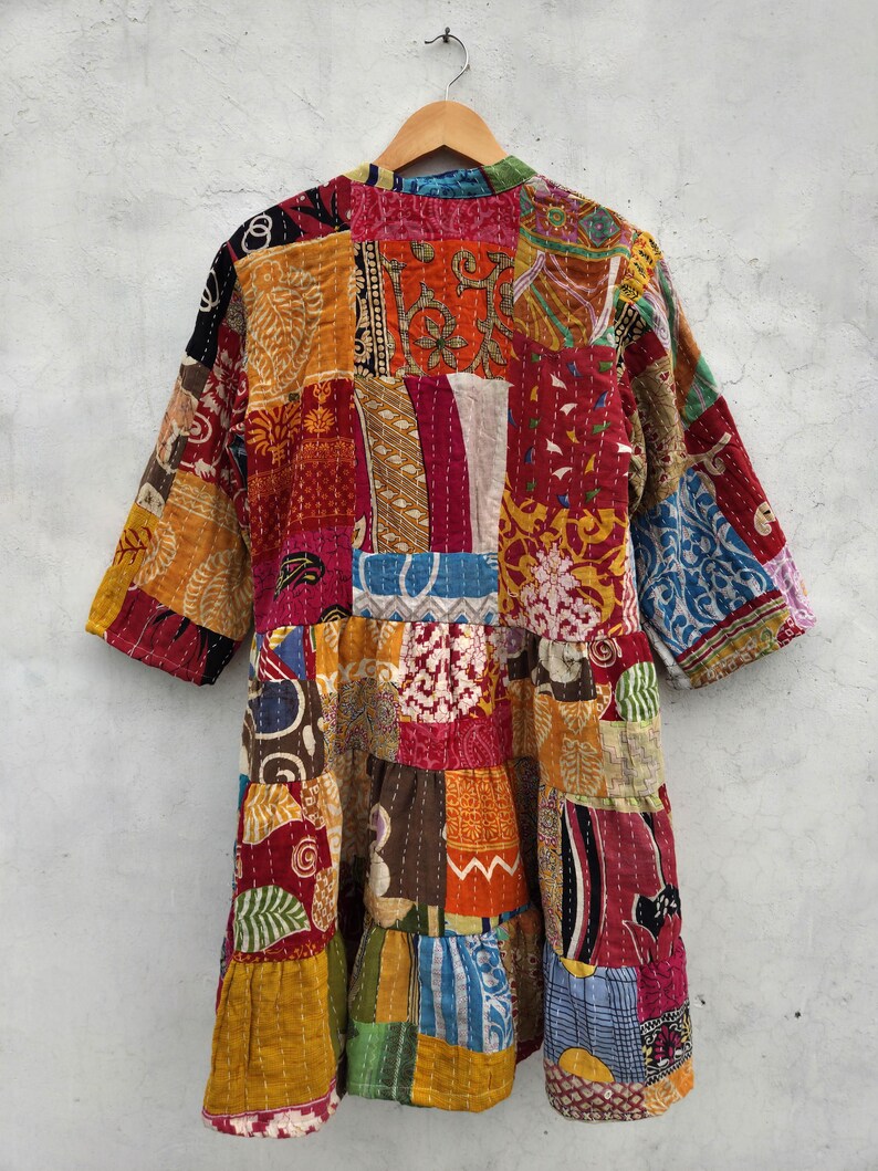 May include: A patchwork jacket with a variety of colorful fabric squares. The jacket has three-quarter sleeves and a tiered design. The colors include red, orange, yellow, blue, and green.