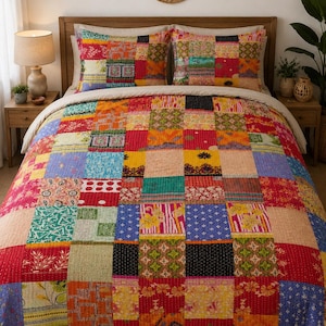 Könnte beinhalten: Eine Patchwork-Tagesdecke und zwei passende Kissenbezüge mit einem lebendigen Raster aus bunten Stoffquadraten. Das Textil zeigt eine Vielzahl komplizierter Blumen-, geometrischer und abstrakter Muster in Rot-, Gelb-, Blau- und Grüntönen.