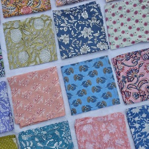 May include: A collection of square fabric napkins with various floral and botanical patterns. The napkins feature a range of colors, including yellow, blue, pink, and green. The designs include large flowers, leaves, and intricate patterns, suitable for home decor or dining.