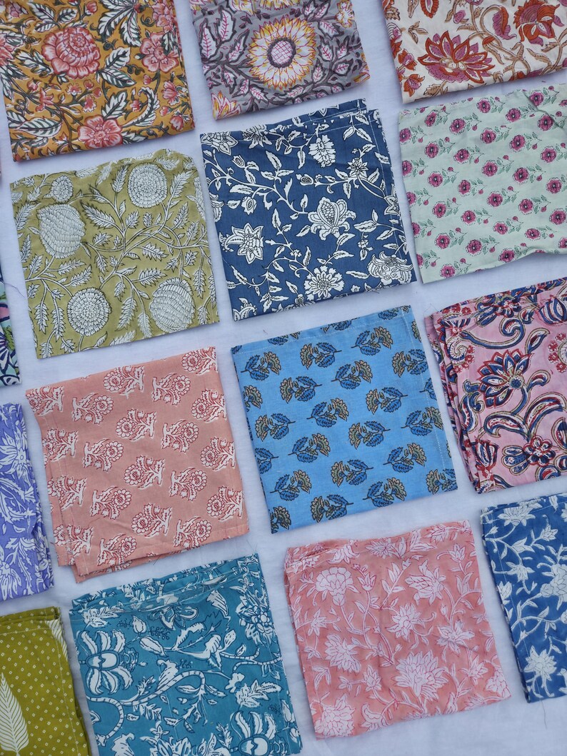 May include: A collection of square fabric napkins with various floral and botanical patterns. The napkins feature a range of colors, including yellow, blue, pink, and green. The designs include large flowers, leaves, and intricate patterns, suitable for home decor or dining.