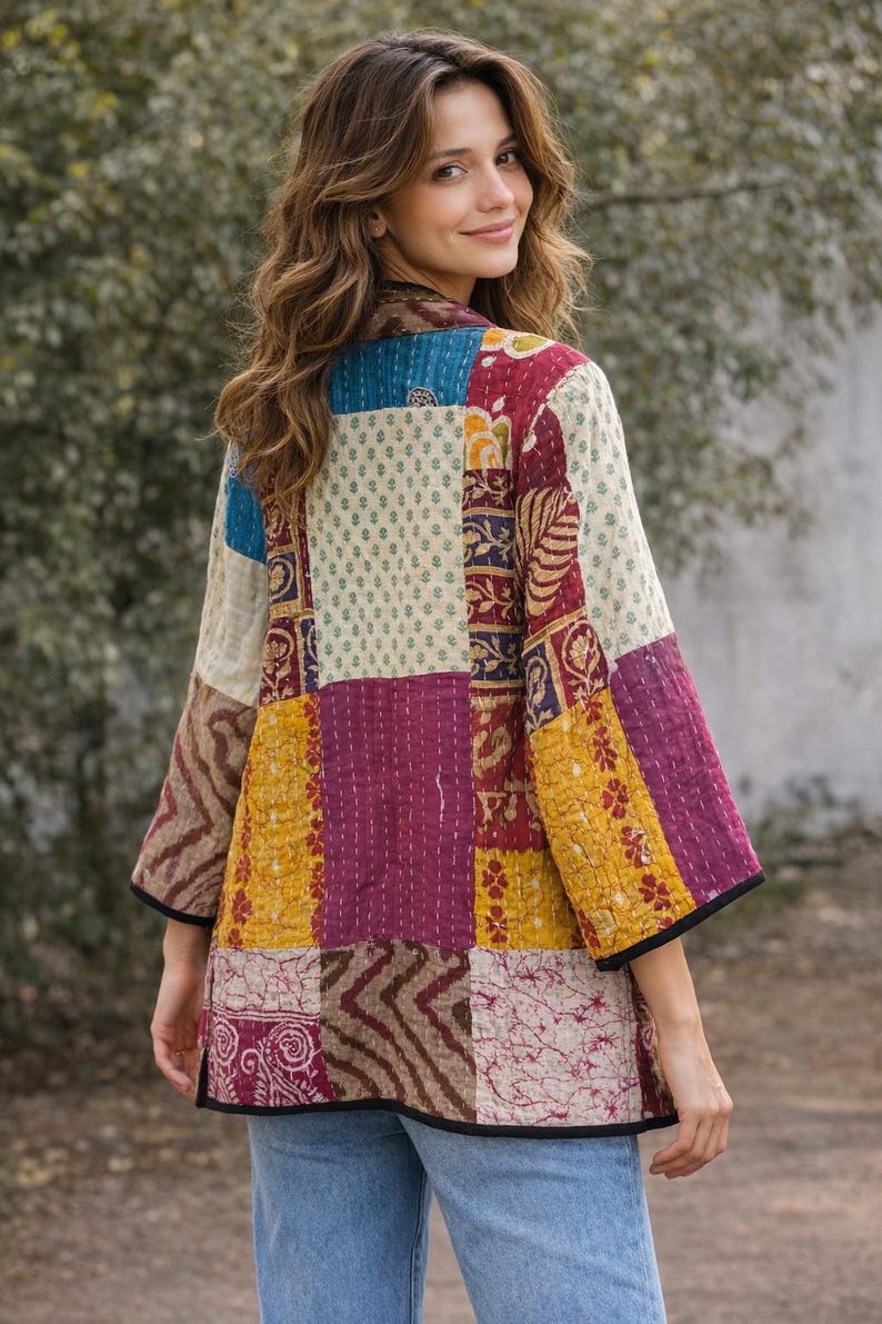 May include: A quilted jacket featuring a patchwork design of various floral and geometric patterns in shades of maroon, mustard yellow, cream, and blue. The garment has three-quarter length sleeves, a straight hem, and black trim along the edges.