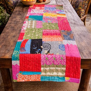 Puede incluir: Un camino de mesa de patchwork colorido con una variedad de patrones y colores, incluyendo rojo, rosa, verde y azul. El camino de mesa est&aacute; colocado sobre una mesa de madera, agregando un toque vibrante al comedor. El camino de mesa mide unos 152 cm de largo.