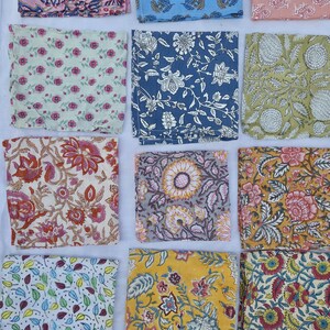 May include: A collection of colorful, square fabric napkins with various floral and leaf patterns. The napkins feature a range of colors, including pink, blue, green, yellow, and gray. Each napkin showcases a unique design, creating a diverse and visually appealing display.