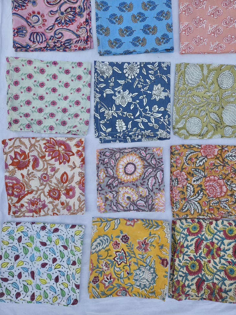 May include: A collection of colorful, square fabric napkins with various floral and leaf patterns. The napkins feature a range of colors, including pink, blue, green, yellow, and gray. Each napkin showcases a unique design, creating a diverse and visually appealing display.