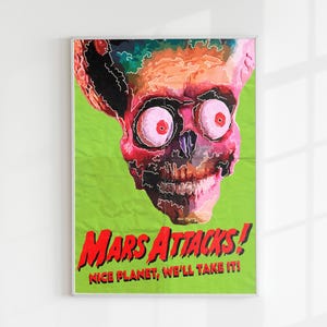 May include: A framed poster featuring a colorful illustration of a Martian skull with large, red eyes against a green background. The poster reads "Mars Attacks! Nice Planet, We'll Take It!" in red and white text.