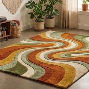 Könnte beinhalten: Ein rechteckiger Teppich mit Retro-Design. Der Teppich hat ein wellenförmiges Muster in Orange-, Gelb-, Grün- und Weißtönen. Der Teppich liegt auf einem Betonboden in einem Raum mit Pflanzen und einem Plattenspieler.