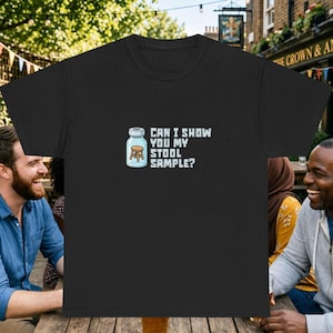 Può includere: Una t-shirt nera con la grafica di un piccolo sgabello di legno all'interno di una fiala medica di vetro. Accanto alla fiala, il testo recita: CAN I SHOW YOU MY STOOL SAMPLE? Il design utilizza un carattere pixelato ed è centrato sul davanti.