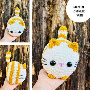 May include: A handmade, white and orange striped crochet cat toy. The cat has black eyes, whiskers, and a pink nose. The text "MADE IN CHENILLE YARN" is in a white circle. The cat's tail is upright.