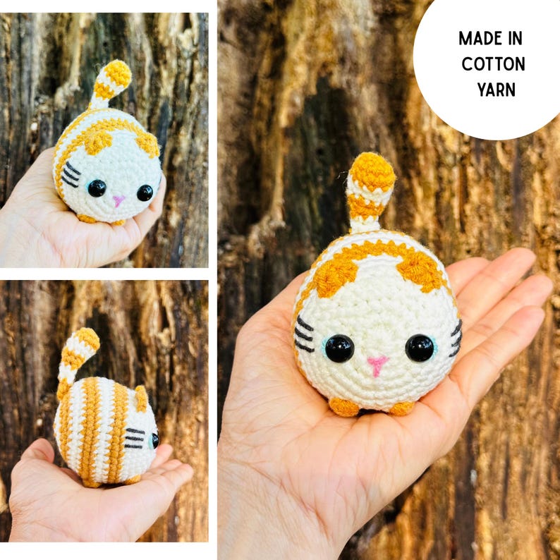 May include: A handmade crochet cat toy in white and orange. The cat has large black eyes, a pink nose, and small orange paws. The tail is striped orange and white. The text "MADE IN COTTON YARN" is in a white circle.