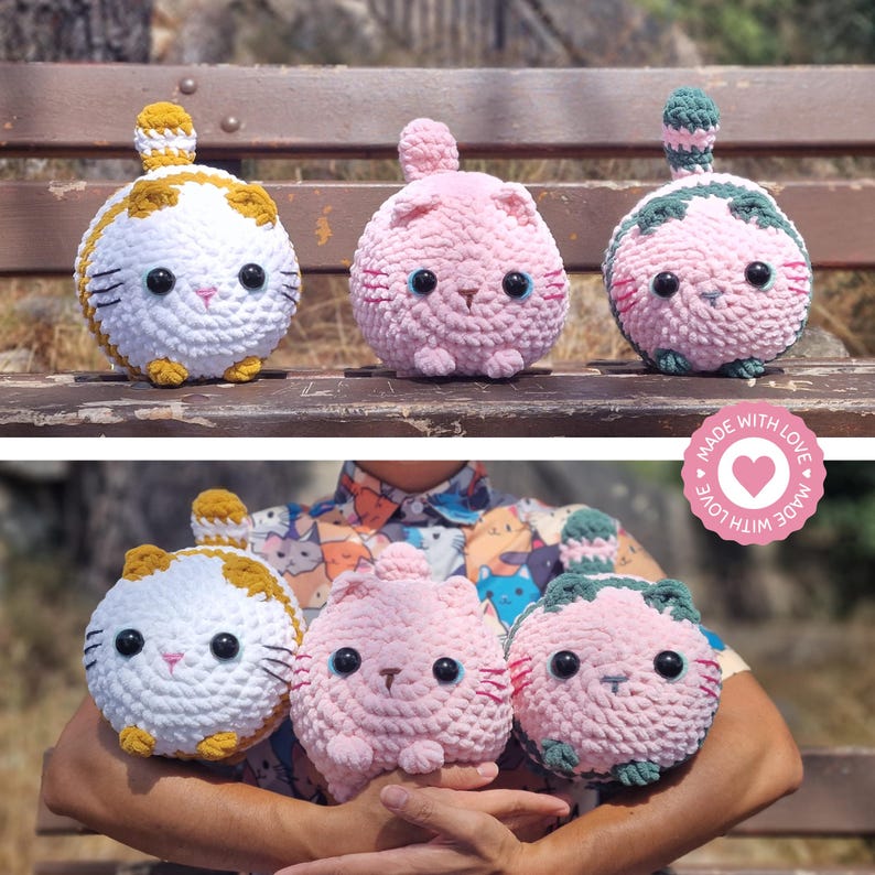May include: Three handmade crochet cat plushies in white, pink, and green. The white cat has orange accents, the pink cat has blue eyes, and the green cat has pink accents. Each plush has a round body, a small tail, and a cute face. The image includes the text "MADE WITH LOVE".