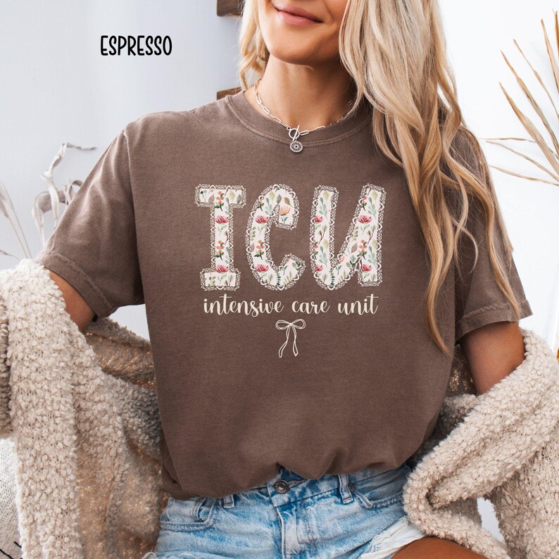 A "Espresso" Comfort Colors t-shirt, featuring the letters "ICU" in a block font filled with a green, pink, and white floral pattern with a decorative border, and the words "intensive care unit" and a bow below.