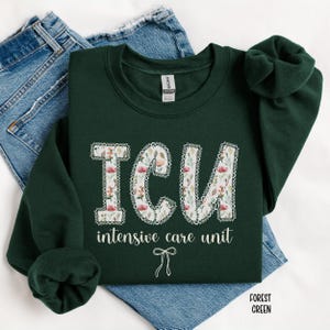 A "Forest Green" sweatshirt, featuring the letters "ICU" in a block font filled with a green, pink, and white floral pattern with a decorative border, and the words "intensive care unit" and a bow below.