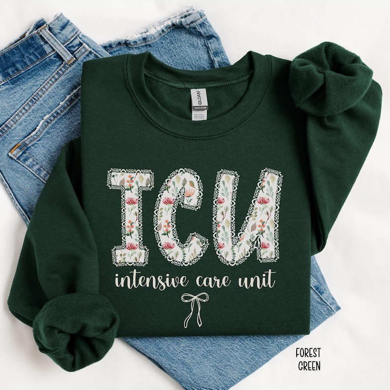 A "Forest Green" sweatshirt, featuring the letters "ICU" in a block font filled with a green, pink, and white floral pattern with a decorative border, and the words "intensive care unit" and a bow below.