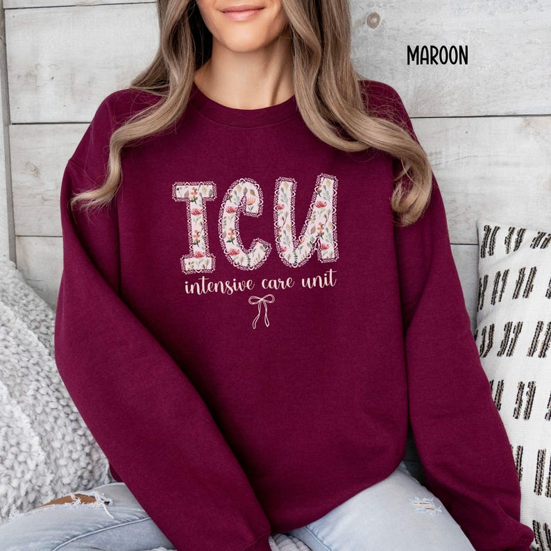 A "Maroon" sweatshirt, featuring the letters "ICU" in a block font filled with a green, pink, and white floral pattern with a decorative border, and the words "intensive care unit" and a bow below.