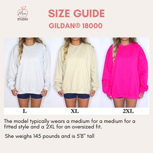 A size guide for Gildan 18000 sweatshirts, showing a model wearing sizes L, XL, and 2XL in different colors. Text explains the model's typical size (Medium for fitted, 2XL for oversized) and dimensions: 5'8" tall, 145 pounds.