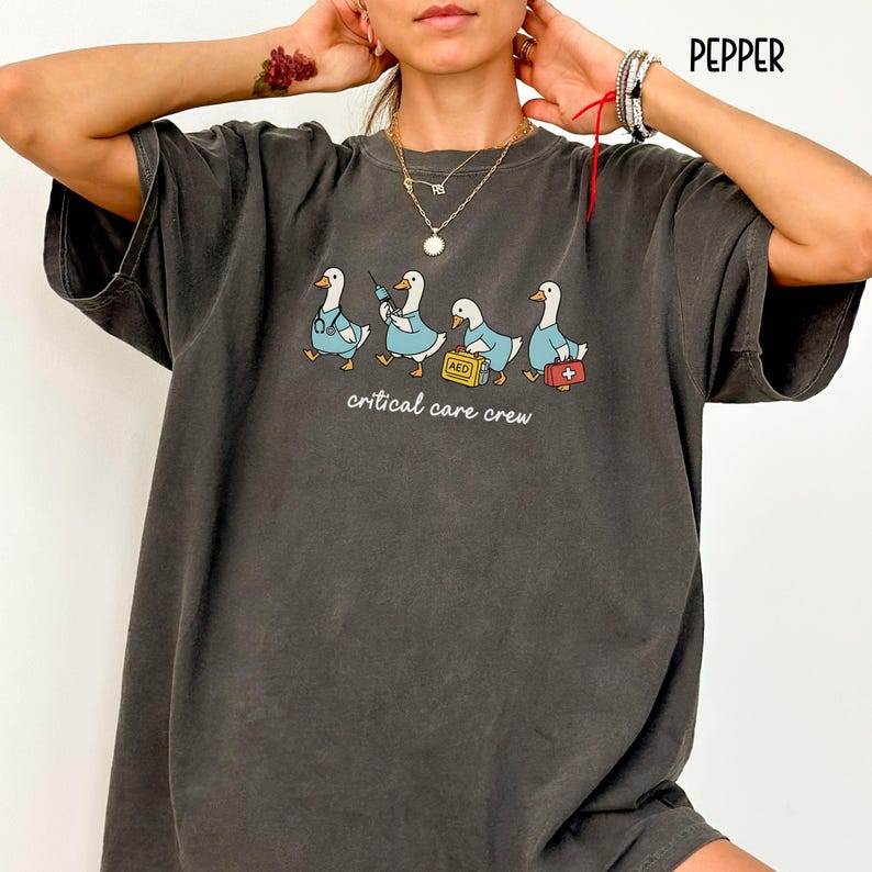 A "Pepper" Comfort Colors t-shirt featuring four cartoon geese dressed as an ICU medical team, with the text "critical care crew" printed below.