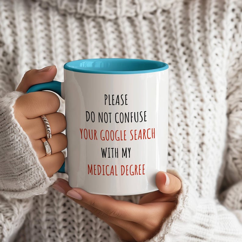 White ceramic mug with a light blue handle and interior, featuring 'PLEASE DO NOT CONFUSE YOUR GOOGLE SEARCH WITH MY MEDICAL DEGREE' in red and black.