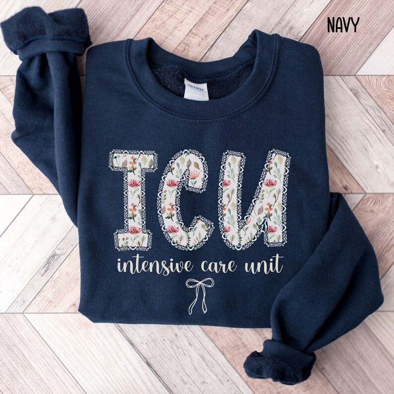 A "Navy" sweatshirt, featuring the letters "ICU" in a block font filled with a green, pink, and white floral pattern with a decorative border, and the words "intensive care unit" and a bow below.