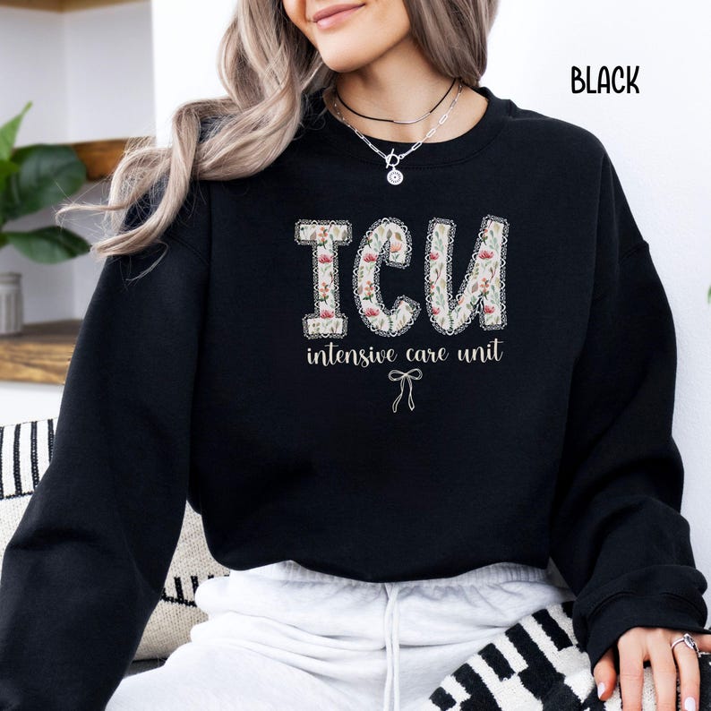 A "Black" sweatshirt, featuring the letters "ICU" in a block font filled with a green, pink, and white floral pattern with a decorative border, and the words "intensive care unit" and a bow below.