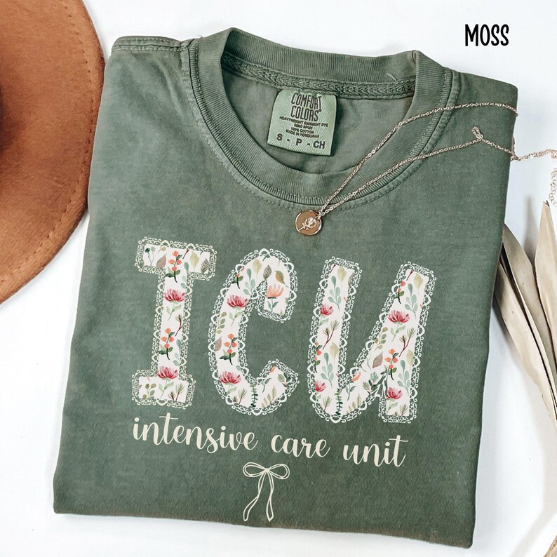 A "Moss" Comfort Colors t-shirt, featuring the letters "ICU" in a block font filled with a green, pink, and white floral pattern with a decorative border, and the words "intensive care unit" and a bow below.