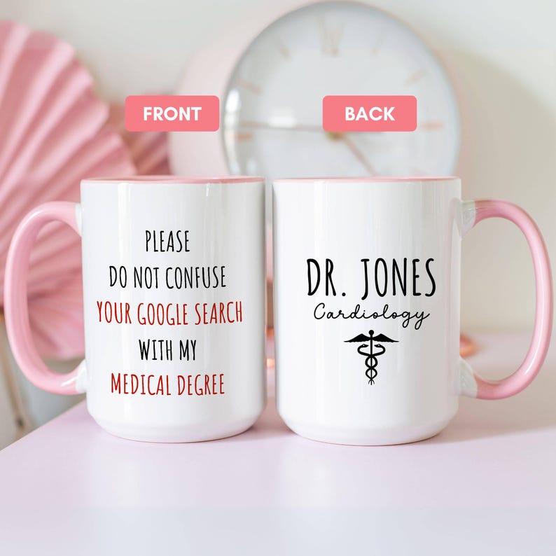 White ceramic mug with a pink handle and interior, featuring 'PLEASE DO NOT CONFUSE YOUR GOOGLE SEARCH WITH MY MEDICAL DEGREE' in red and black. The back displays a personalized design with 'Dr. Jones Cardiology' and a medical symbol.