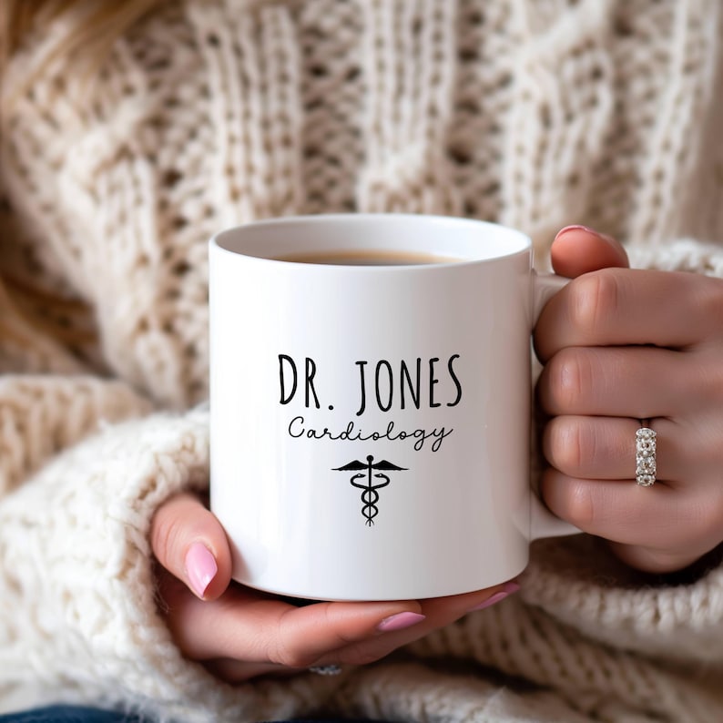 White ceramic mug features a custom personalized design with 'Dr. Jones Cardiology' and a medical symbol.