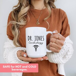 White ceramic mug features a custom personalized design with 'Dr. Jones Cardiology' and a medical symbol.