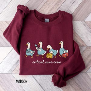 A "Maroon" sweatshirt, featuring four cartoon geese dressed as an ICU medical team, with the text "critical care crew" printed below.