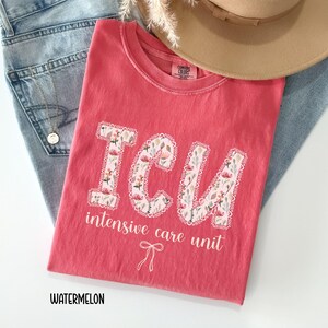 A "Watermelon" Comfort Colors t-shirt, featuring the letters "ICU" in a block font filled with a green, pink, and white floral pattern with a decorative border, and the words "intensive care unit" and a bow below.
