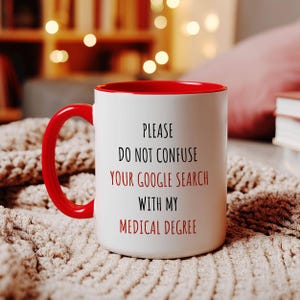 White ceramic mug with a red handle and interior, featuring 'PLEASE DO NOT CONFUSE YOUR GOOGLE SEARCH WITH MY MEDICAL DEGREE' in red and black.