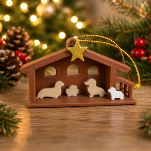 May include: A brown plastic nativity scene ornament featuring a gold star at the peak of the roof. Inside the structure are four small, light-colored dog figurines arranged in a row. A gold string is attached to the top for hanging purposes.