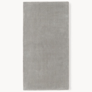 May include: A rectangular, light gray rug with a soft, textured surface. The rug is displayed against a white background, showcasing its solid color and simple design. The rug's dimensions are not visible.
