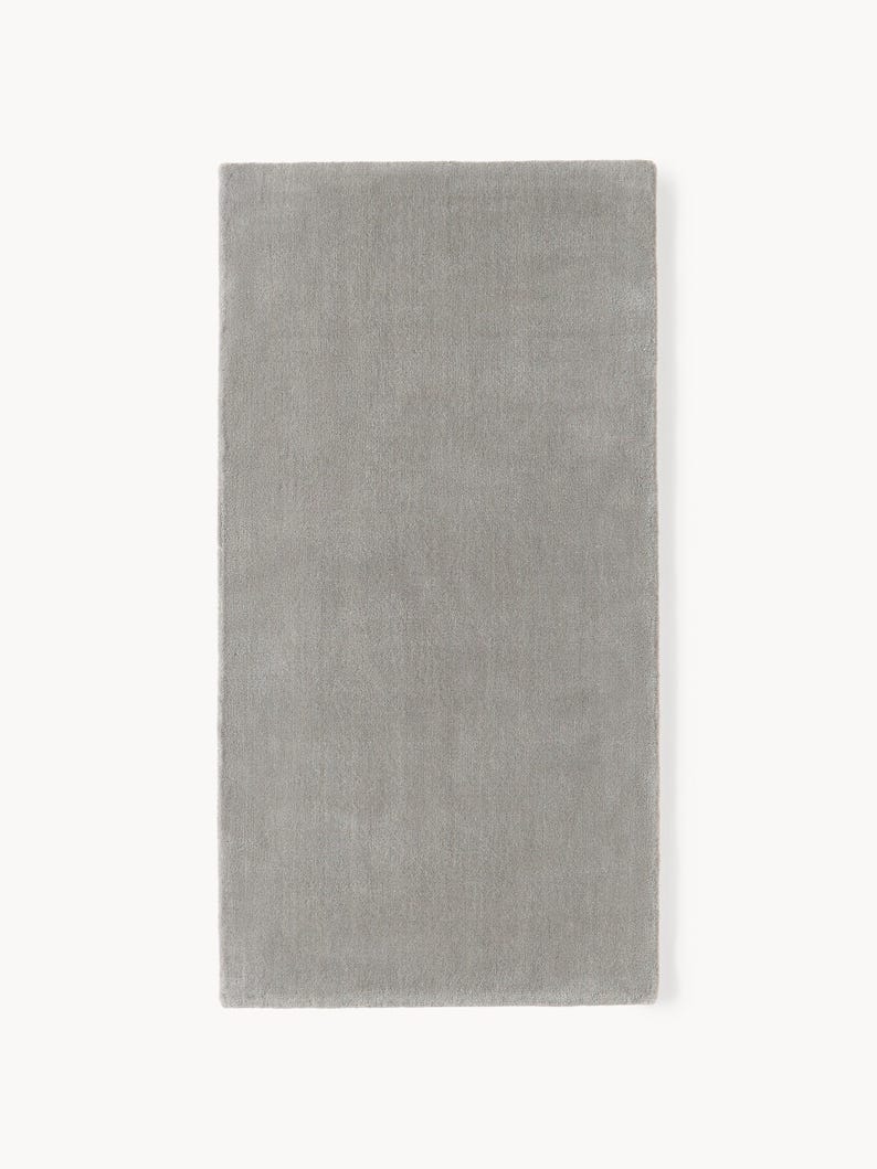 May include: A rectangular, light gray rug with a soft, textured surface. The rug is displayed against a white background, showcasing its solid color and simple design. The rug's dimensions are not visible.