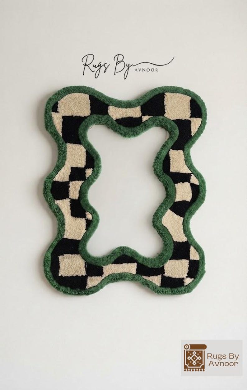 Hand tufted checkerboard mirror frame with a forest green border hanging on a plain off-white wall.